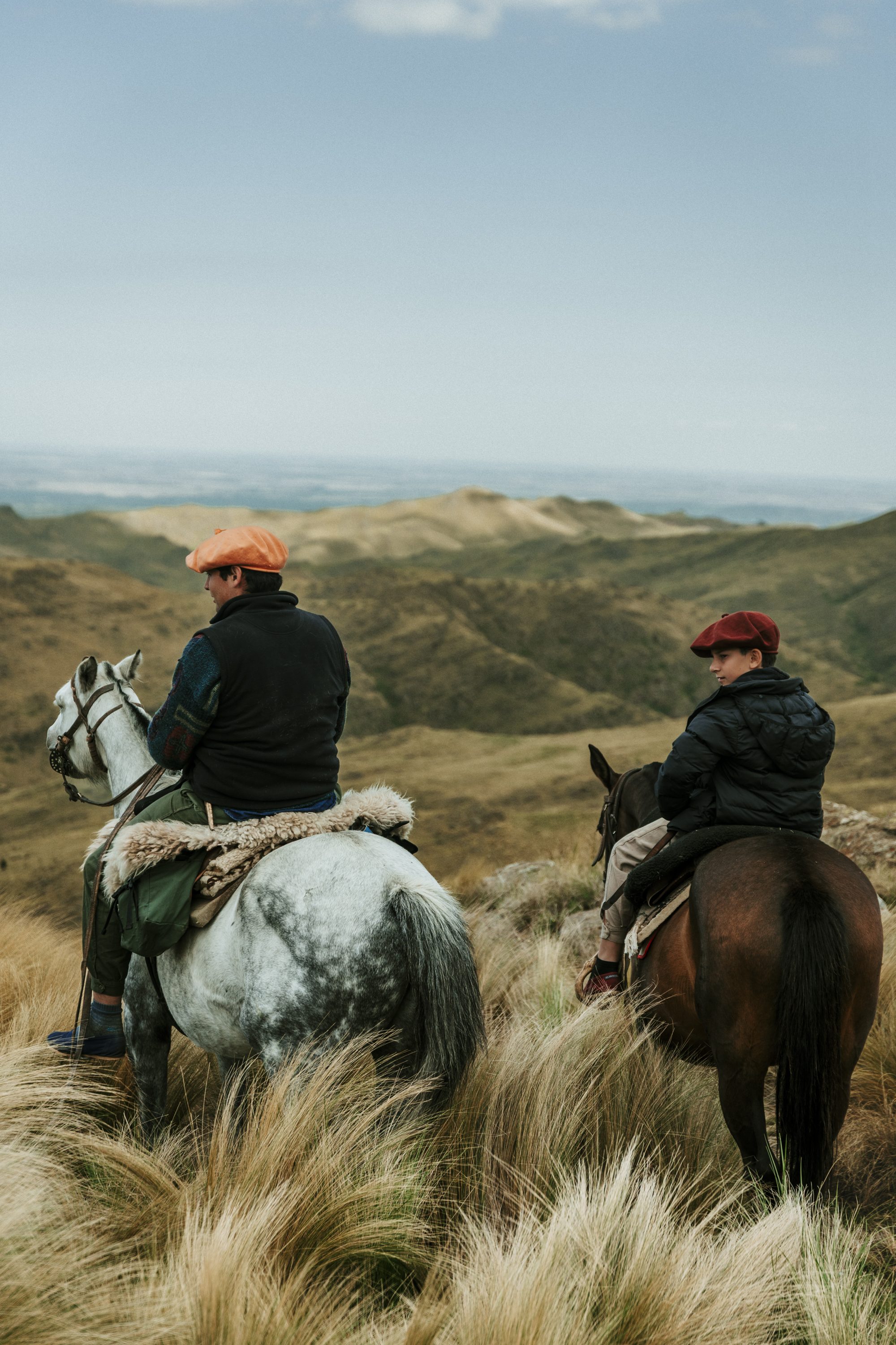 Two riders look over the valley from the ridge