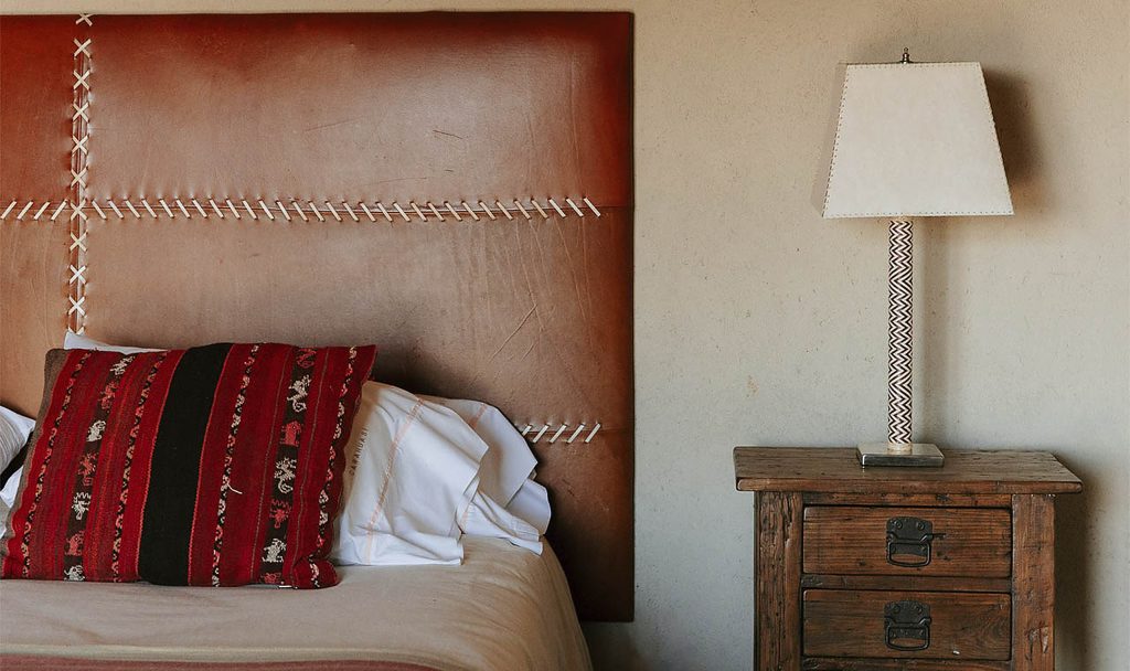 Leather headboard with woven kilim cushion in a Carahuasi bedroom