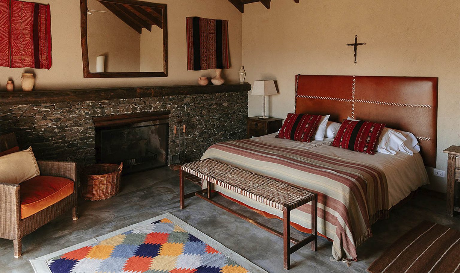 The master bedroom at Carahuasi — stone fireplace, kilim rug, and handmade textiles