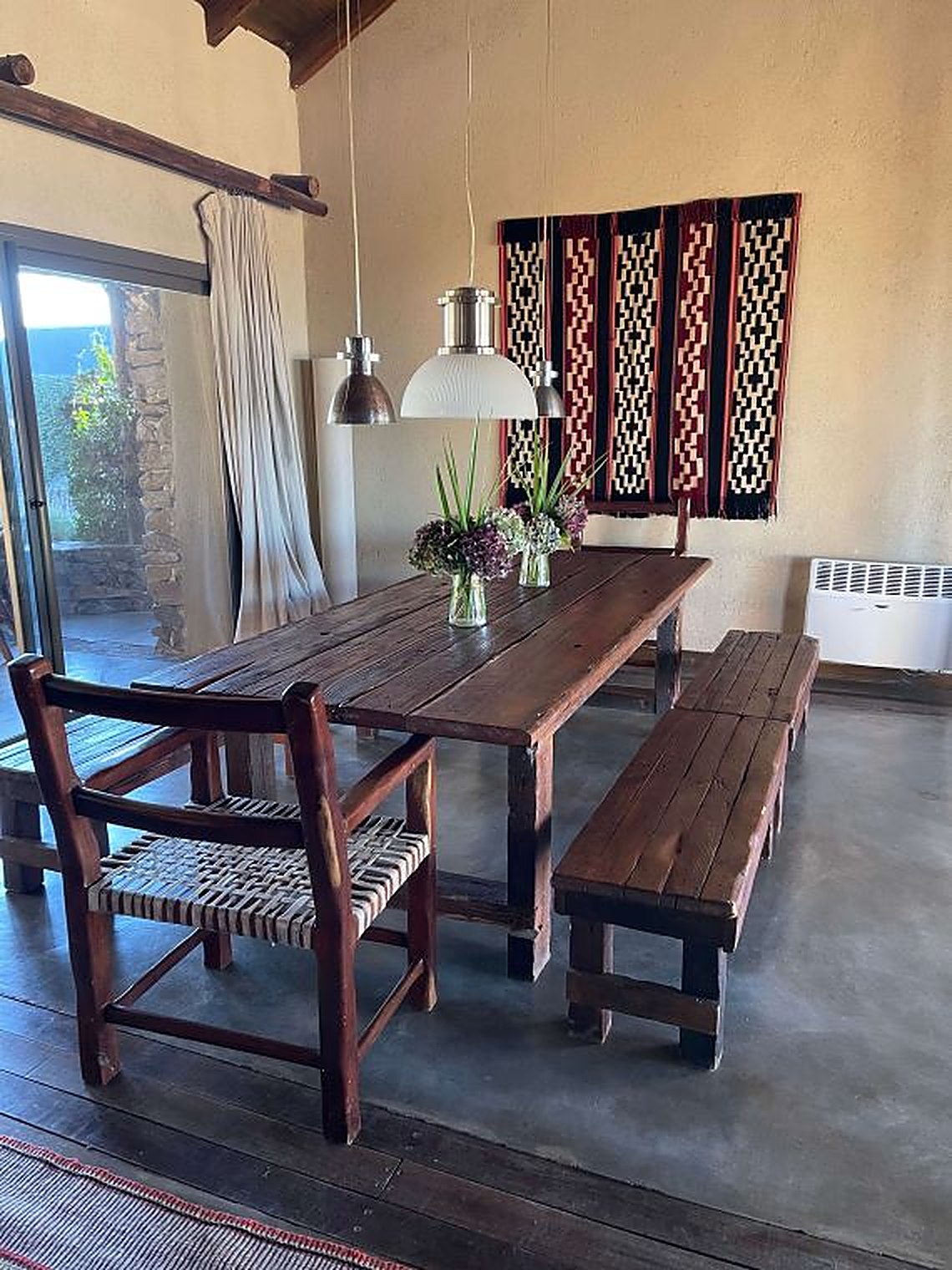 The open living and dining room at Carahuasi — long table, stone fireplace, handmade textiles